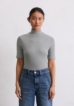 Grijze geribbelde coltrui met korte mouwen, gecombineerd met high-waisted denim broek met knoopsluiting en een relaxte pasvorm.