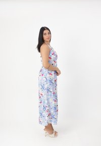 Robe maxi florale aux tons bleus, rouges et blancs avec un design à col halter. Fabriquée en tissu léger avec une silhouette fluide.