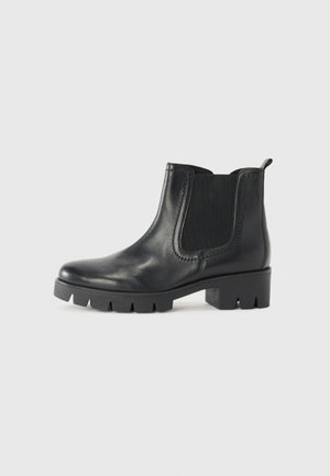Black leather ankle boot with elastic side panels, round toe, and chunky rubber sole featuring pronounced tread. Minimalist design and smooth texture.