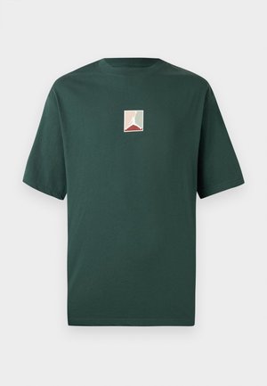 Tricou scurt cu mânecă verde din bumbac, cu un logo pătrat ce prezintă o siluetă albă pe un fundal pastel. Guler clasic rotund.