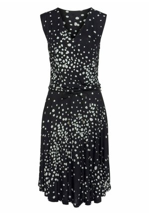 Black sleeveless dress featuring a V-neck, cinched waist, and scattered white polka dots. Made of a soft, flowing fabric.