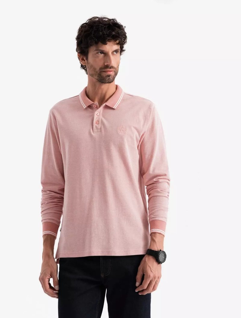 Pitkähihaine vaaleanpunainen polo paita, jossa on kontrastiväriset kaulusraidat, pienellä logolla rinnassa ja teksturoidusta kankaasta. Yhdistetty tummiin farkkuihin.