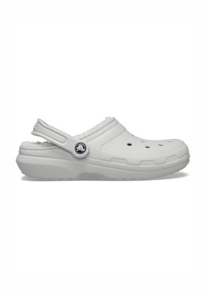 Weißer Slip-On Clog mit Belüftungslöchern, verstellbarem Fersenriemen, strukturierter Sohle und Logoemblem an der Seite.