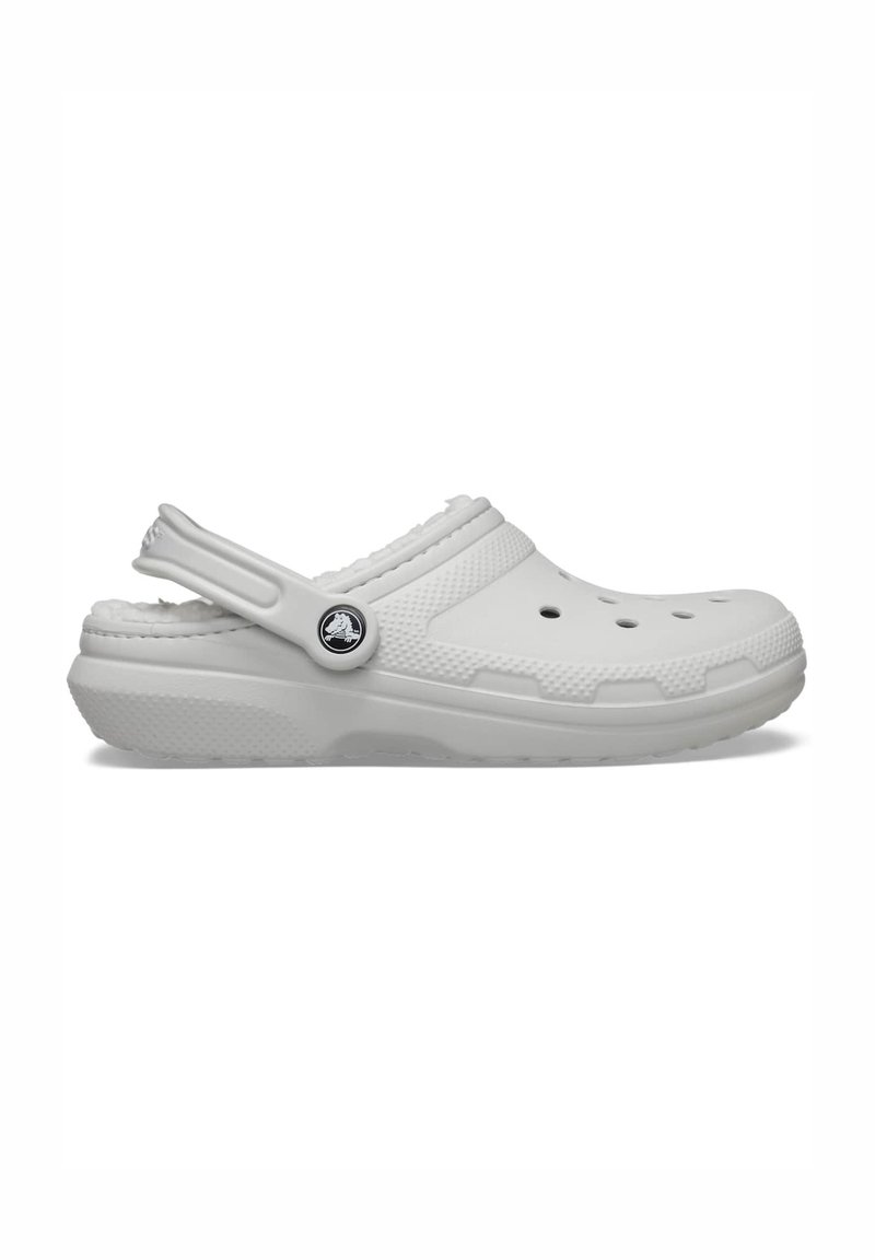 Sabot blanc sans lacets avec des trous de ventilation, une bride de talon ajustable, une semelle texturée et un emblème logo sur le côté.