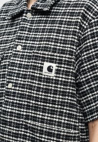 Zwart-wit geruit overhemd met korte mouwen en Carhartt-logo op het borstzakje.