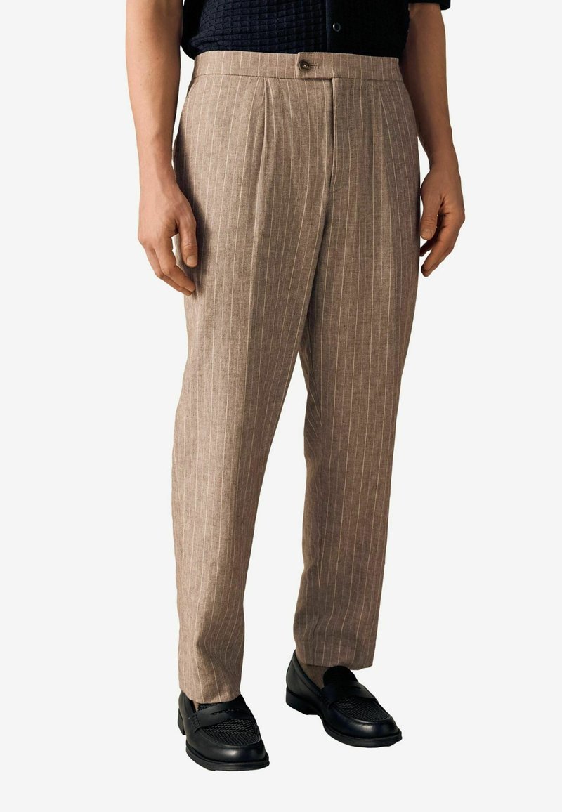 Lysebrune stribede bukser med skræddersyet design, der har en knaplukning og et tekstureret stof, parret med sorte loafers.