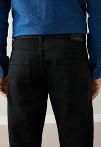 Svarta jeans i denim med en figurnära design. Har bakfickor med kurvad sömnad och en lädermärke med varumärkeslogotyp vid midjan.