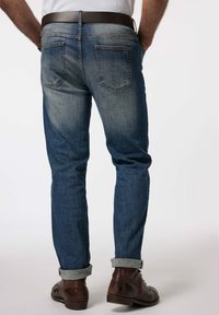 Jeans i en blekt blå tvätt med en avsmalnande passform, med två bakfickor och uppvikt fåll. Matchat med bruna läderstövlar.