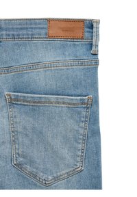 Poche arrière en jean denim bleu clair avec couture orange et étiquette de marque en cuir marron sur la ceinture, sur fond blanc.