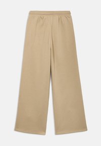 Béžové nohavice s širokými nohavicami a elastickým pásom, vyrobené z mäkkej tkaniny, s hladkou textúrou bez viditeľných vzorov či doplnkov.