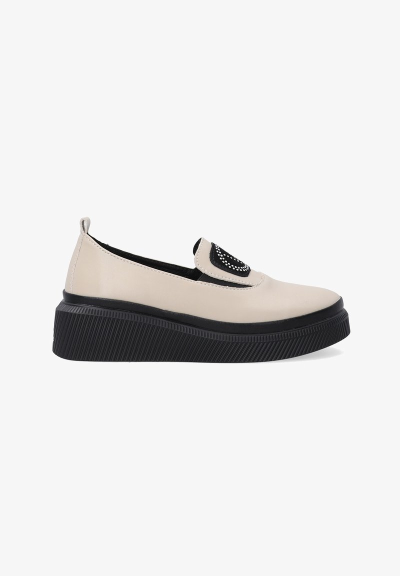 Beige Slipper mit einer schwarzen strukturierten Plattformsohle, die eine dekorative schwarze Akzent mit Strasssteinen im oberen Bereich aufweist.