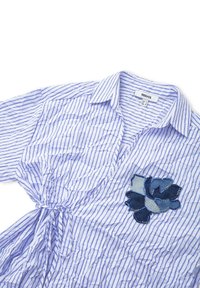 Camicia a righe in blu chiaro e bianco, con un patch in denim floreale. Realizzata in tessuto leggero, con vita legata e colletto.
