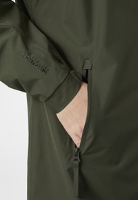 Waterdichte olijfgroene jack met een gladde textuur, voorzien van een ritszak en merkdetails op de mouw. Naadloos ontwerp verbetert de duurzaamheid.