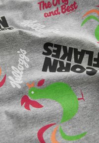 Gray fabric featuring colorful graphics of a green rooster, red accents, and various text, including "Kellogg's" and "Corn Flakes."