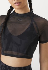 Top atlético negro corto hecho de material transparente, con un escote redondo y el logo de ICIW en el pecho, que destaca un diseño ajustado.