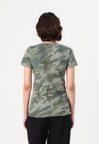 T-skjorte med korte ermer laget av myk bomull i et grønt camouflasjemønster med varierende nyanser, med klassisk rund hals og en tettsittende fasong.