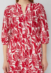 Rotes und weißes Blumenmuster Kleid mit V-Ausschnitt, drei Viertelärmeln und gerafftem Taillenbereich. Hergestellt aus leichtem Stoff mit lässiger Passform.