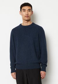 Marineblauer Strickpullover mit Rundhalsausschnitt, gerippten Bündchen und Saum. Die strukturierte Stoff zeigt verstreute hellere Partien.