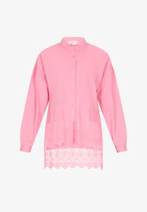 Vaaleanpunainen nappipaita pitkillä hihoilla, jossa on läpinäkyvä pitsireunus alareunassa ja pystytakki kerroksellista ilmettä varten.