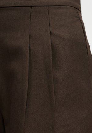 Dark brown tailored garment with vertical pleat detail on smooth fabric surface.