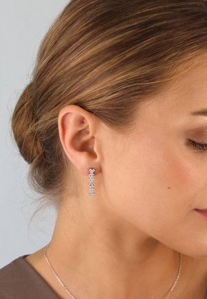 Silverne Ohrringe in linearer Form, verziert mit mehreren kleinen, funkelnden Edelsteinen und einem zarten Tropfendesign. Eleganter und leichter Look.