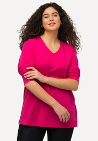 Tričko s dlouhým rukávem, V-výstřih, v jasně růžové barvě, vyrobené z příjemné bavlny, s ohrnutými rukávy a bočními rozparky pro pohodlí a volnost pohybu.