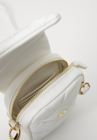 Λευκή τσάντα από τεχνητό δέρμα με χρυσές λεπτομέρειες, φερμουάρ, ποιότητα με κουβάρτα και εσωτερικές θήκες για κάρτες. Συμπαγής και οργανωμένος σχεδιασμός.