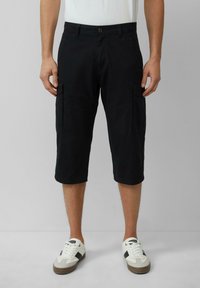 Zwarte cargoshorts van een katoenmengsel, knielengte, met zijzakken en een knoopsluiting, gecombineerd met witte sneakers.