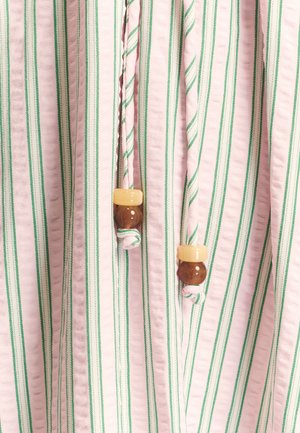 Tela a rayas en rosa y verde con una superficie texturizada. Tiene cordones con cuentas de madera marrones y amarillas como detalles.