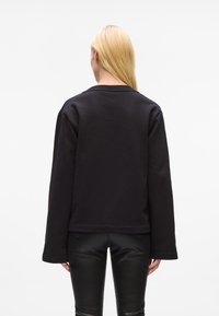 Svart hettegenser med en boksformet passform, lange ermer og rund hals. Myk stoff med en jevn tekstur, med minimale detaljer.