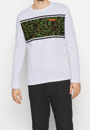 Langärmliges T-Shirt aus weißer Baumwolle mit einem grünen und braunen Camouflage-Panel über der Brust, das schwarze Streifen und das orangefarbene "Abstract"-Logo zeigt.