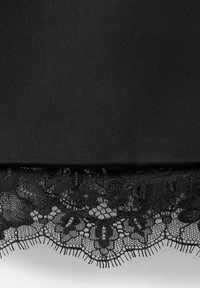 Tejido negro con un dobladillo de encaje con borde ondulado con intrincados patrones florales y bordes redondeados, que contrasta con una superficie textil lisa.