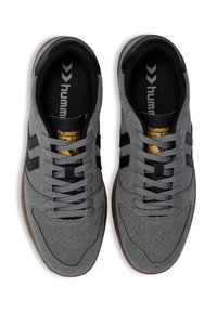 Szare buty sportowe z teksturowanej tkaniny, czarnymi akcentami i szarymi sznurówkami. Posiadają zaokrąglony nosek i brązową gumową podeszwę.