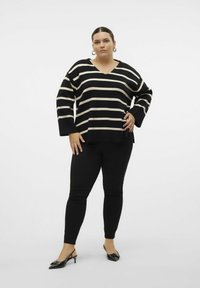 Czarny i kremowy sweter w paski o luźnym kroju z dekoltem w serek, w połączeniu z czarnymi spodniami slim fit i czarnymi butami na obcasie typu slingback.
