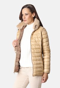 Chaqueta acolchada dorada con un collar de piel sintética y un forro marrón con estampado de reptil; cuenta con un cierre de cremallera y bolsillos laterales.