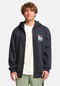 Sudadera con cremallera en color marino hecha de una tela suave, con un bolsillo estilo canguro, capucha con cordón y un gráfico colorido en el lado izquierdo del pecho.