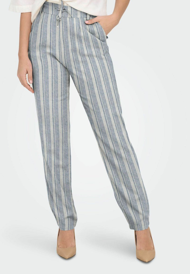 Pantalons légers à rayures bleues et beiges avec une taille élastique, deux poches latérales et une coupe décontractée. Associés à des talons nus.