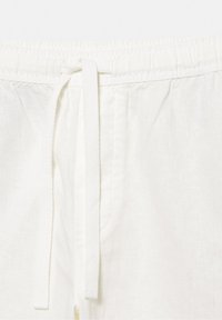 Pantaloni albi din in, cu talie elastică și șnur frontal legat într-un nod lejer.