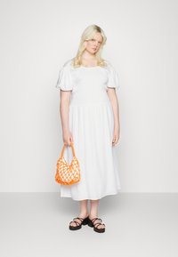 Vestido branco de mangas bufantes com corpete franzido, combinado com uma bolsa de rede laranja e sandálias pretas de tiras. Textura suave e design de comprimento médio.