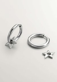 Pendientes de aro de plata con un diseño elegante, donde un aro está adornado con un charm en forma de estrella y una pieza de estrella separada. Acabado metálico suave.