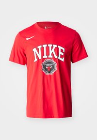 Punane puuvillane T-särk, mille ees on paksustes valgetes tähtedes "NIKE" ja ümmargune Chicago Bullsi logo. Lühikesed varrukad, standardne lõige.