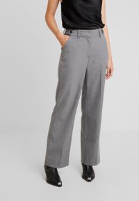 Šedé přesně střižené kalhoty se rovnou nohavicí, jedním zakládam a bočními kapsami. Materiál má jemnou strukturu a je vybaven dvojicí knoflíků na pase.