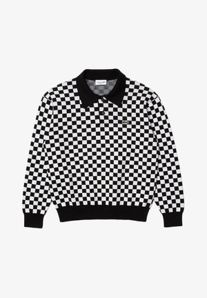 Mustavalkoinen ruudullinen pitkähihainen poolopaita, jossa on musta kaulus, kaksi nappia ja pieni vihreä Lacoste-logo vasemmassa rinnassa.