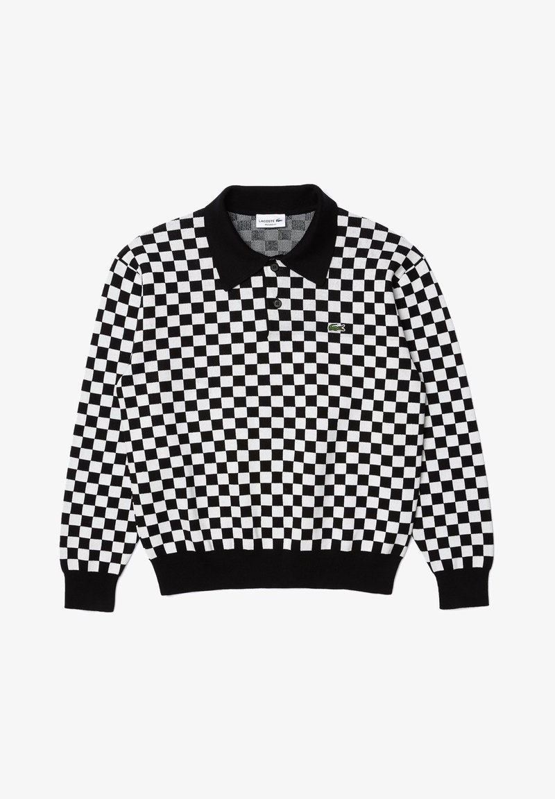 Polo à manches longues à carreaux noirs et blancs avec col noir, deux boutons et petit logo vert Lacoste sur la poitrine gauche.