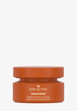 Bol ovale à double couche de couleur orange mat avec une texture lisse. L'étiquette de texte blanche indique "ORIGINS GINZING CRÈME RICHE ÉNERGISANTE."