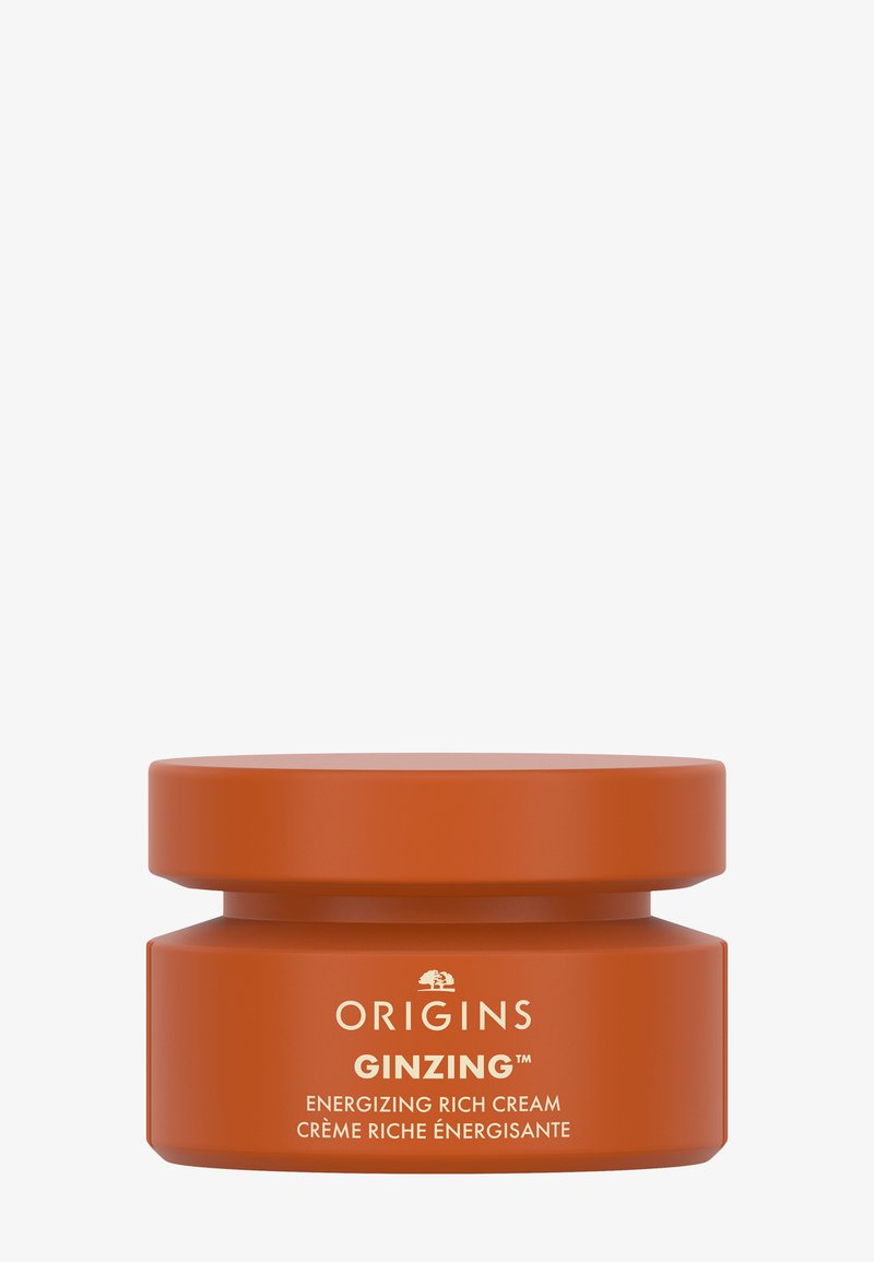 Bol ovale à double couche de couleur orange mat avec une texture lisse. L'étiquette de texte blanche indique "ORIGINS GINZING CRÈME RICHE ÉNERGISANTE."