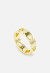 Anello in metallo dorato con una superficie liscia e lucida, caratterizzato da ritagli circolari e simboli incisi. Design leggero e moderno con dettagli accentuati.