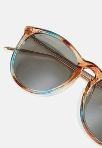 Kissanäkö sunglasses, joissa on oranssi ja sininen värikyllästetty kehys, harmaasutuiset linssit ja metallinen yksityiskohta temppeleissä.