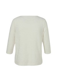 Haut long à manches 3/4 texturé blanc cassé avec un col bateau, vu de dos sur un fond blanc.