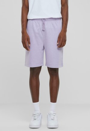 Shorts en coton lilas avec une taille élastique et un cordon de serrage, dotés de poches latérales et d'une coupe décontractée, associés à des baskets blanches.